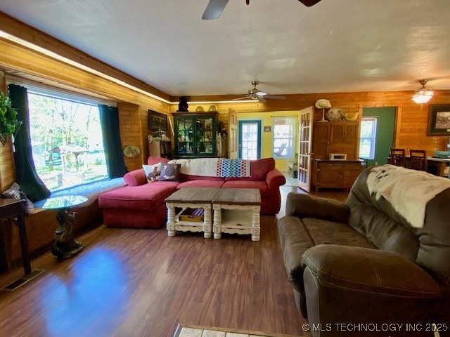 living room featuring a ceiling fan, wood finished floors, and wooden walls