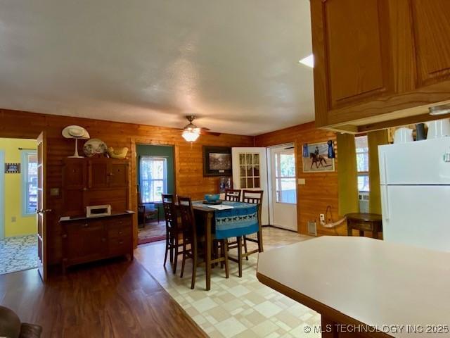 dining space with wood walls, a ceiling fan, and wood finished floors