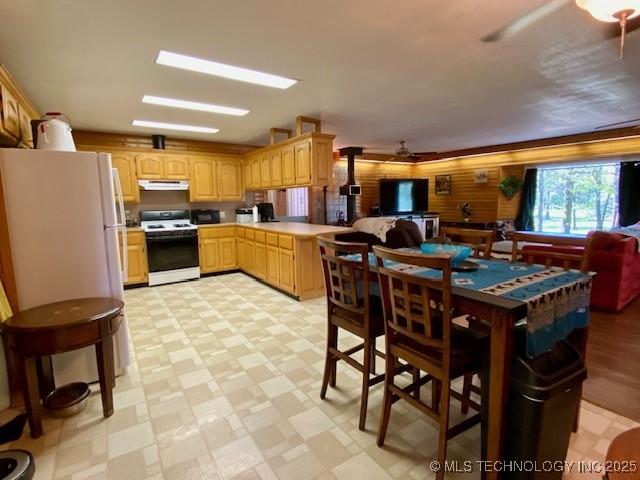 kitchen with light brown cabinetry, gas range gas stove, light floors, light countertops, and under cabinet range hood