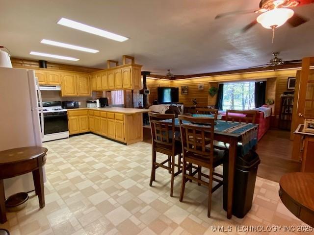 kitchen with white appliances, a ceiling fan, open floor plan, and under cabinet range hood