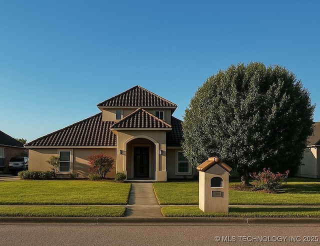 mediterranean / spanish-style home with a tiled roof, a front lawn, and stucco siding