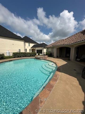 view of swimming pool featuring a pool with connected hot tub, a patio, and fence