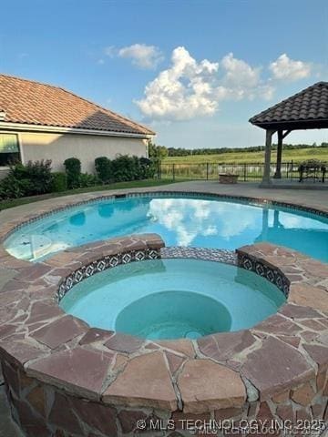 view of pool featuring a gazebo, a pool with connected hot tub, and fence