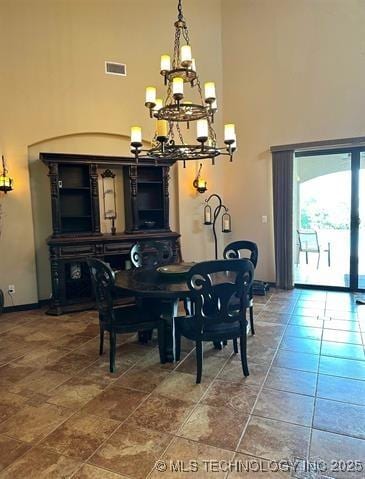 dining room featuring a high ceiling, baseboards, a notable chandelier, and visible vents