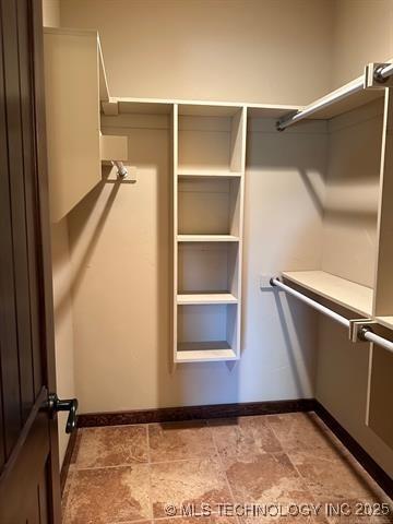 walk in closet with stone finish floor