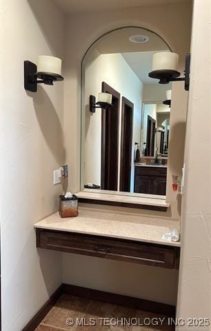 hall featuring baseboards and dark tile patterned flooring
