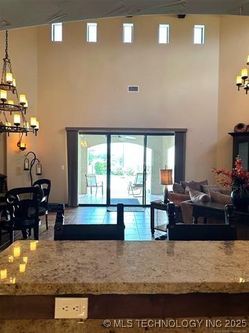 kitchen featuring a high ceiling, light stone counters, a chandelier, and visible vents