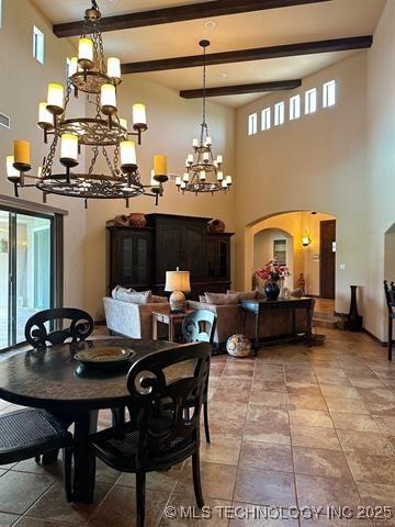 dining area with a high ceiling, an inviting chandelier, visible vents, arched walkways, and beam ceiling