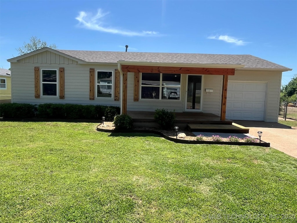 ranch-style home with a front lawn, concrete driveway, an attached garage, covered porch, and roof with shingles