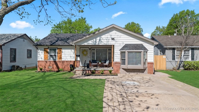 bungalow-style home featuring brick siding, a porch, fence, and a front yard