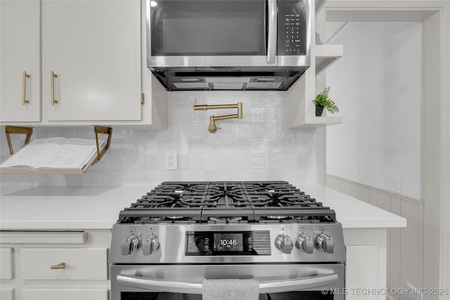 kitchen featuring white cabinets, stainless steel appliances, light countertops, and tasteful backsplash