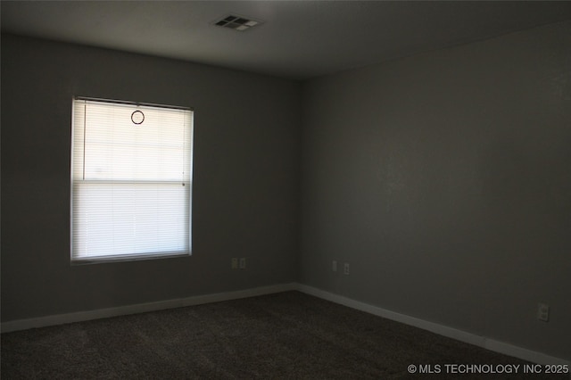 empty room with dark colored carpet, visible vents, and baseboards