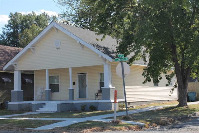 bungalow-style house with roof with shingles and a porch