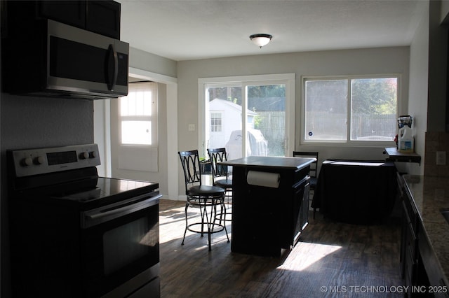 kitchen featuring stainless steel microwave, dark cabinets, electric stove, and dark wood-type flooring