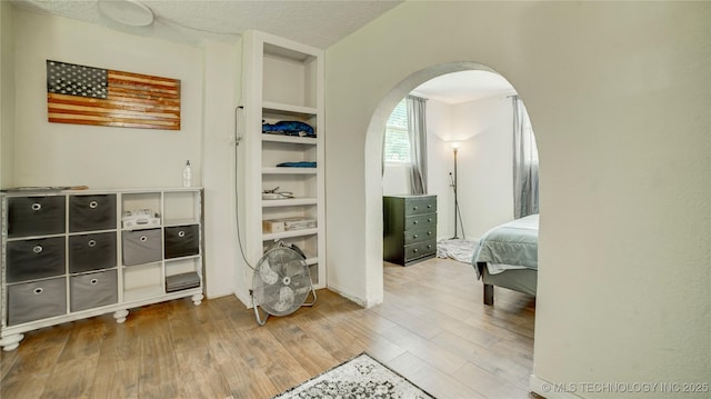 bedroom featuring arched walkways and wood finished floors