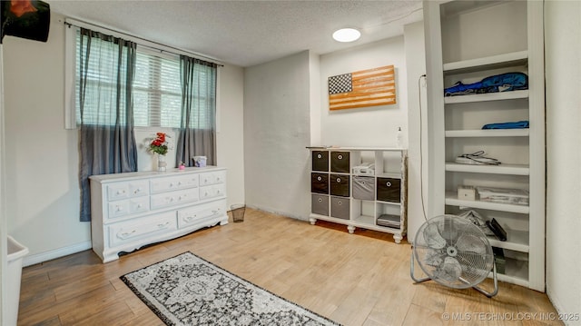 bedroom featuring baseboards, wood finished floors, and a textured ceiling
