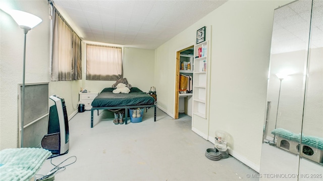 bedroom with baseboards, finished concrete floors, and heating unit