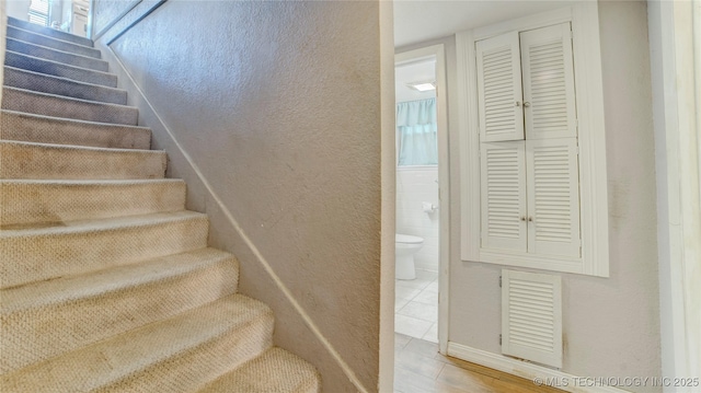 stairs with a textured wall and visible vents