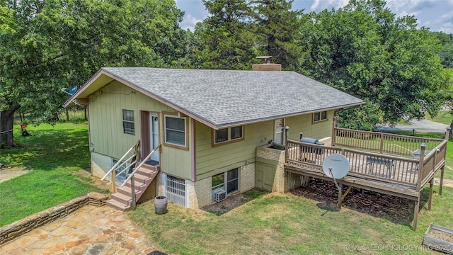back of house featuring roof with shingles, a chimney, entry steps, a deck, and a yard