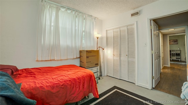 bedroom with visible vents, a textured ceiling, and a closet