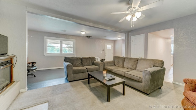 living area featuring baseboards and a ceiling fan
