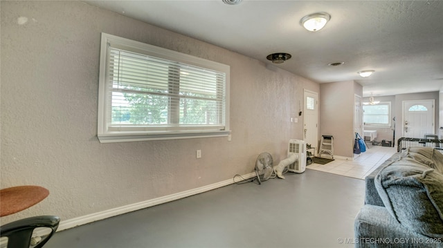 interior space with a textured wall, visible vents, and baseboards