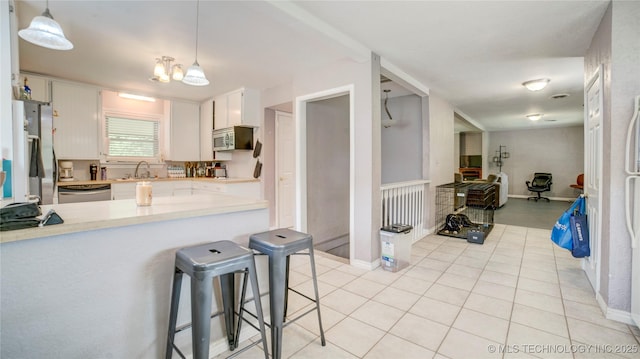 kitchen featuring white cabinets, stainless steel appliances, light countertops, light tile patterned floors, and a peninsula