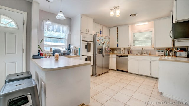 kitchen featuring a sink, light countertops, a peninsula, appliances with stainless steel finishes, and visible vents