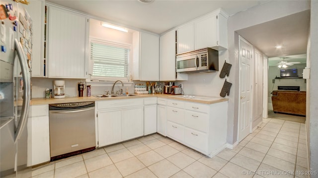 kitchen with light tile patterned floors, stainless steel appliances, light countertops, and a sink
