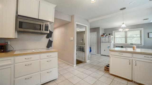 kitchen with stainless steel microwave, an inviting chandelier, light tile patterned floors, and light countertops