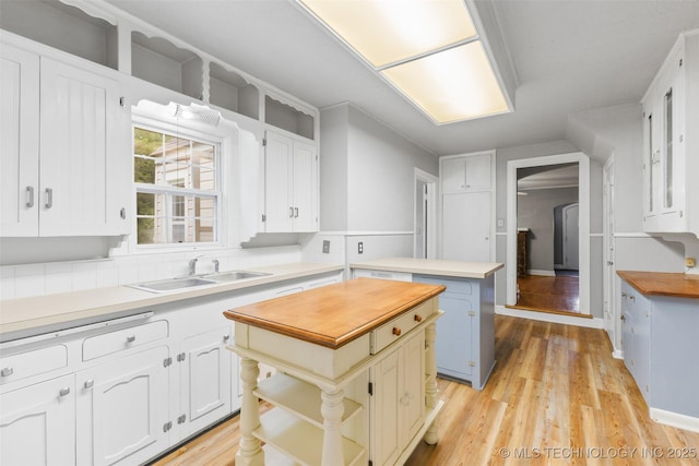 1201 E 18th, Ada, OK 74820 - kitchen featuring a center island, a sink, white cabinets, light wood-style floors, and butcher block countertops