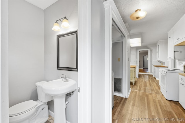 1201 E 18th, Ada, OK 74820 - bathroom featuring visible vents, baseboards, wood finished floors, and toilet