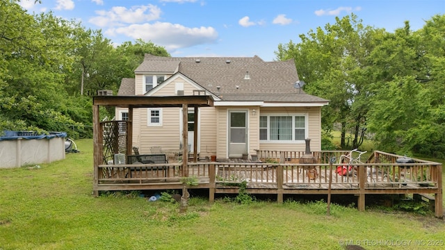 1201 E 18th, Ada, OK 74820 - rear view of house with a shingled roof, a yard, a covered pool, and a deck