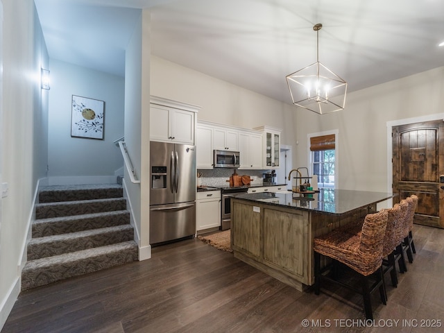 31 Park St, Carlton Landing, OK 74432 - kitchen featuring dark wood-style flooring, a kitchen island with sink, glass insert cabinets, appliances with stainless steel finishes, and a notable chandelier