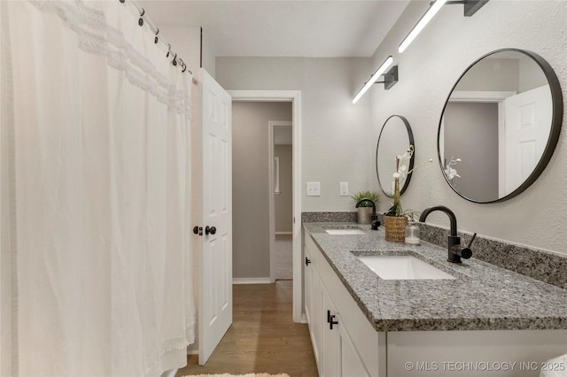 8219 S 67th W Ave, Tulsa, OK 74066 - bathroom featuring double vanity, a textured wall, a sink, and wood finished floors