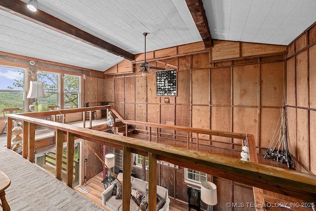 interior space with lofted ceiling with beams, wooden walls, and wood finished floors
