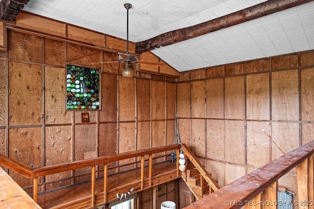 interior space featuring vaulted ceiling with beams and wooden walls