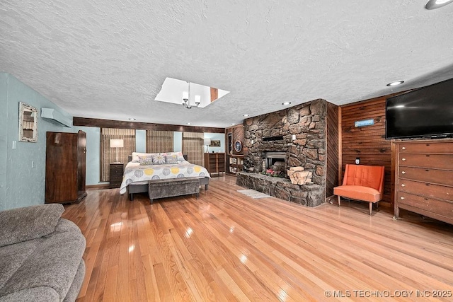 bedroom featuring wood-type flooring, a textured ceiling, wood walls, and a wall unit AC