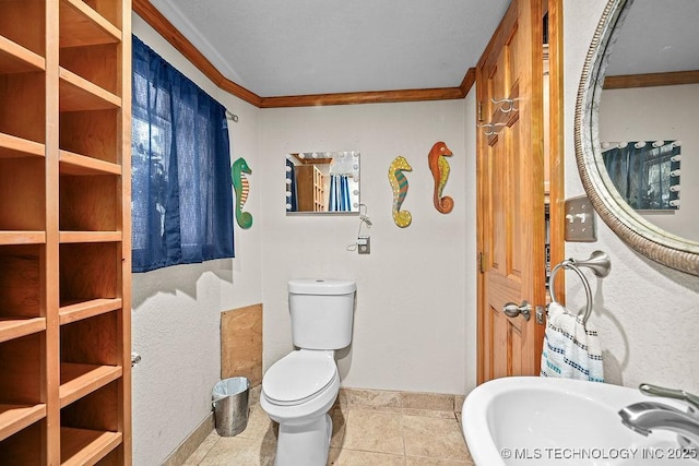 bathroom with toilet, crown molding, a sink, and baseboards