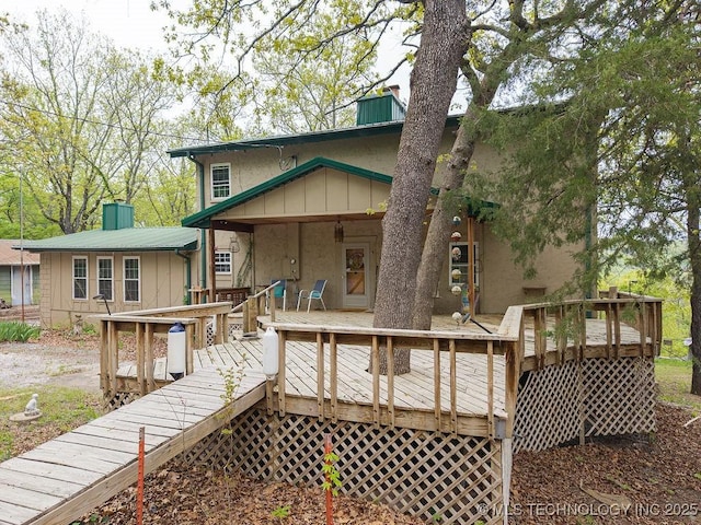 back of house featuring a wooden deck, a chimney, and stucco siding