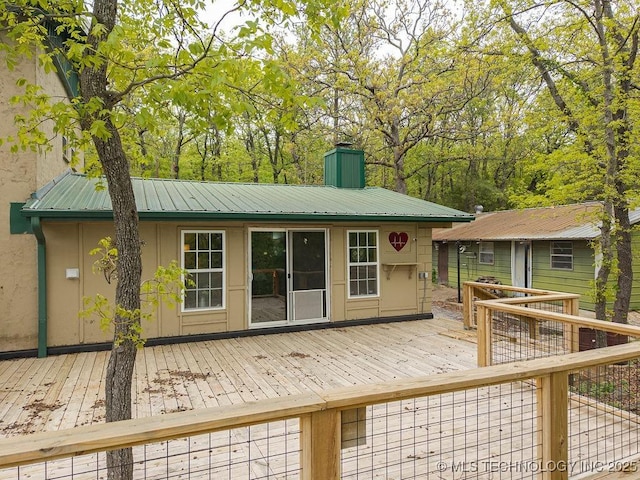 back of property with a chimney and a deck