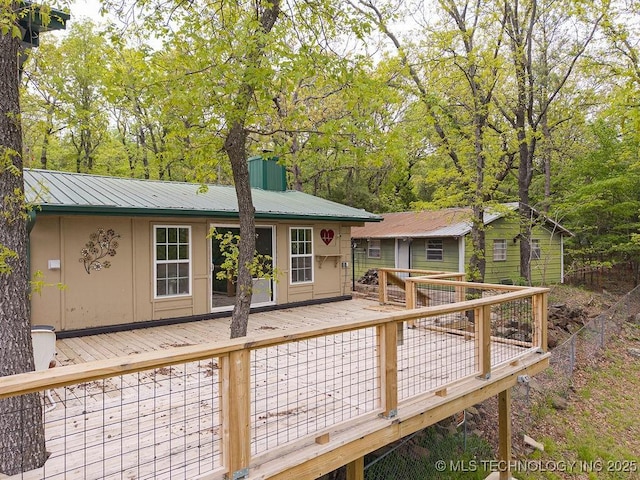 back of house with a chimney, metal roof, and a deck