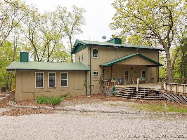 view of front facade with a chimney, concrete block siding, a deck, and metal roof