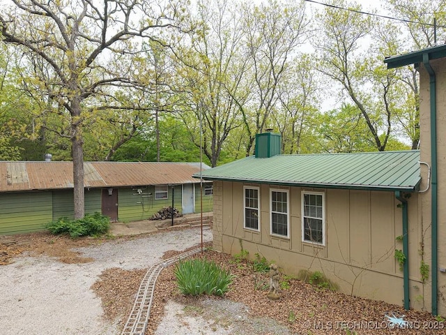 view of property exterior featuring a chimney and metal roof