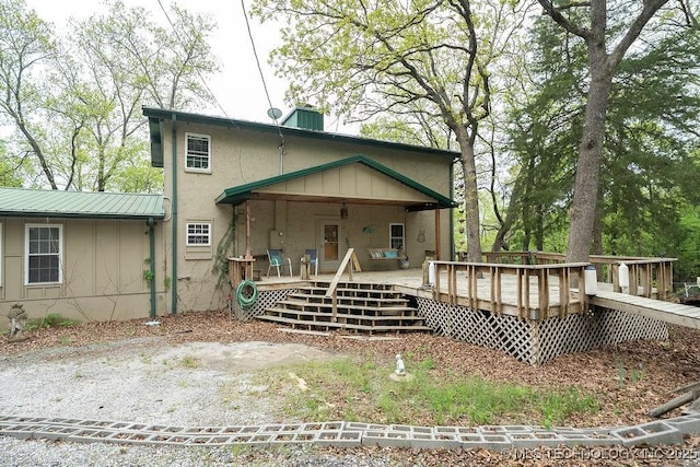 rear view of property with a chimney, a deck, and stucco siding