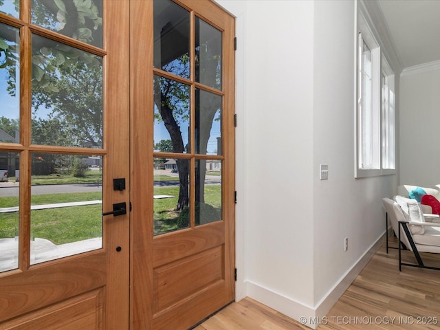 doorway to outside featuring light wood finished floors, baseboards, and crown molding