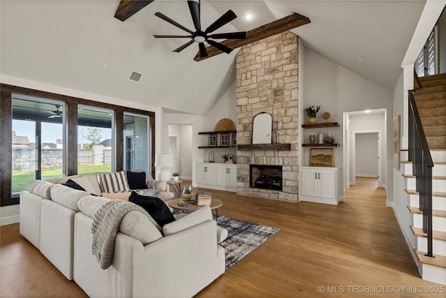 living area with wood finished floors, visible vents, stairs, high vaulted ceiling, and ceiling fan