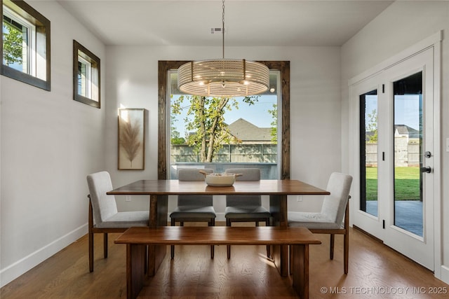 dining area featuring plenty of natural light, baseboards, wood finished floors, and an inviting chandelier