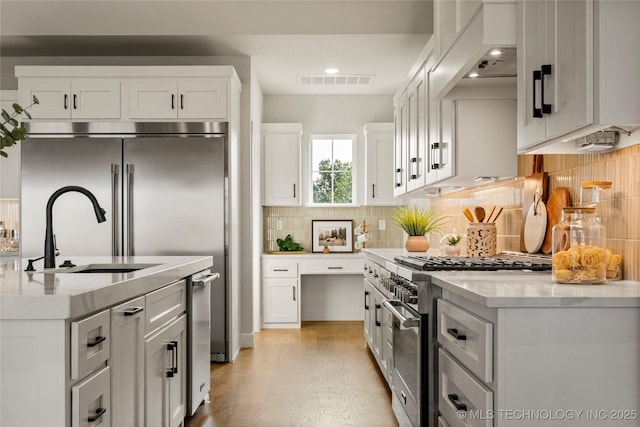13676 S 23rd St, Bixby, OK 74008 - kitchen with high end appliances, custom exhaust hood, tasteful backsplash, white cabinets, and light wood finished floors