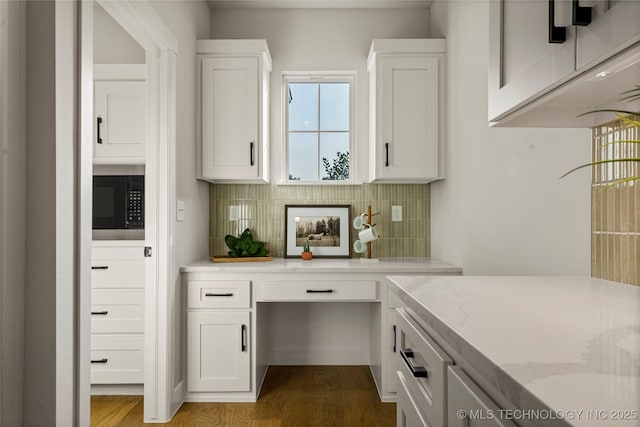 bar with built in microwave, dark wood-type flooring, and decorative backsplash